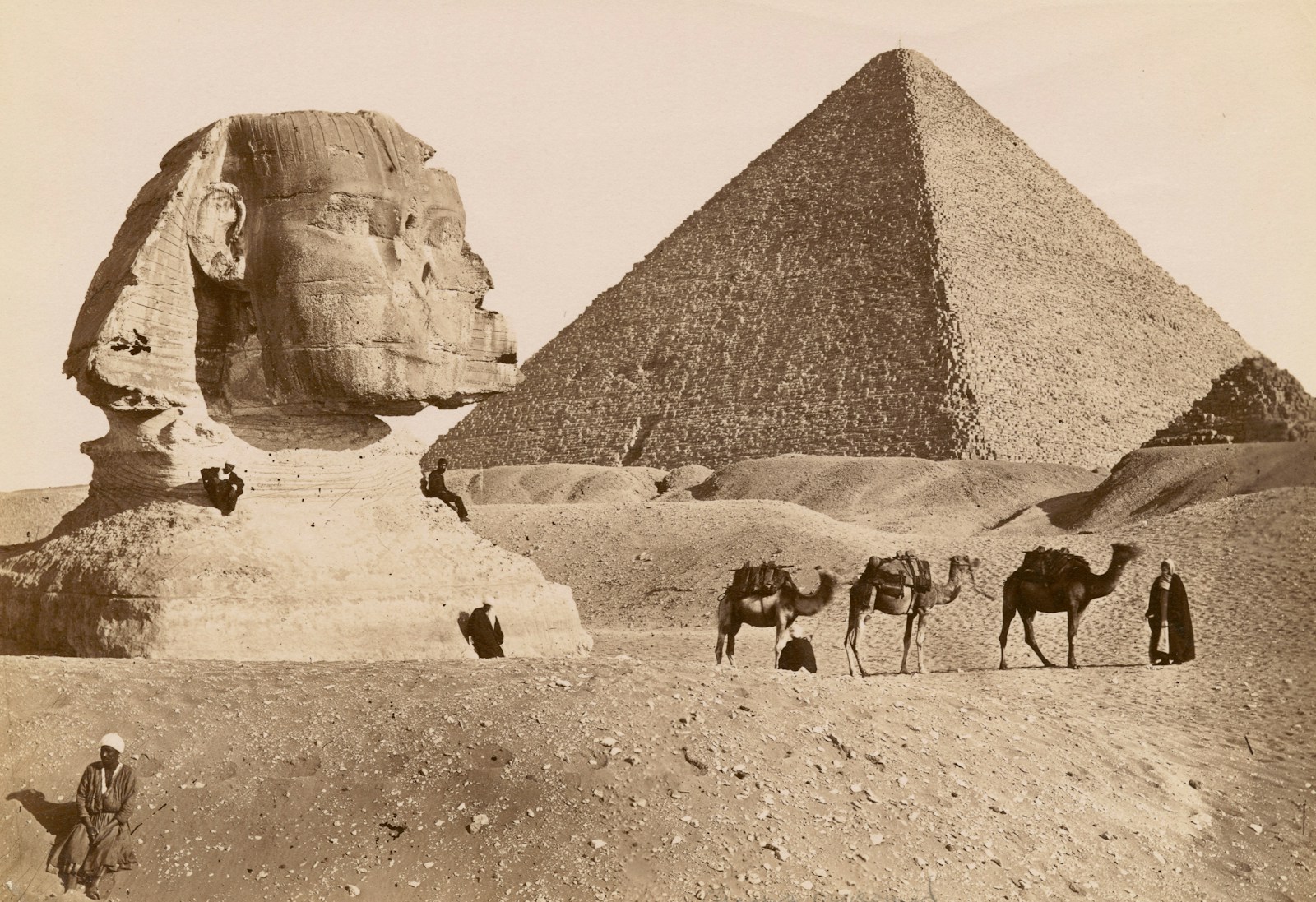 grayscale photo of pyramid and camels in the desert